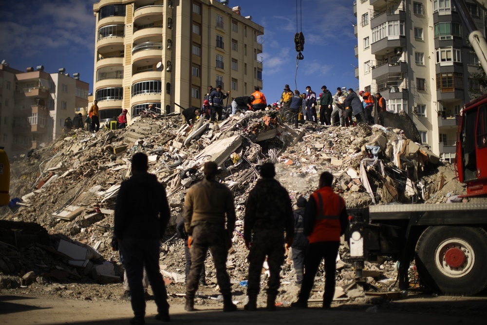 搜救人員在倒塌的建築物瓦礫堆中，尋找可能的倖存者。（美聯社）