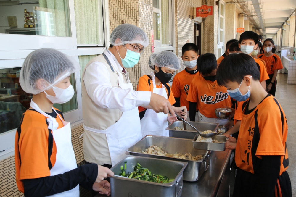 台南市長黃偉哲化身美食突擊檢查員，直訪協進國小營養午餐，幫忙打菜還一起吃飯。（市府提供）

