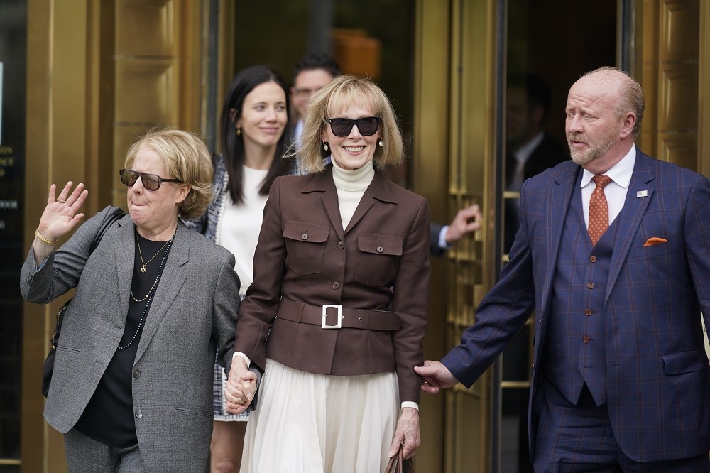 卡洛爾戴著太陽眼鏡微笑，與律師凱普蘭（Roberta Kaplan）一起離開法院，未對記者發言。（美聯社）