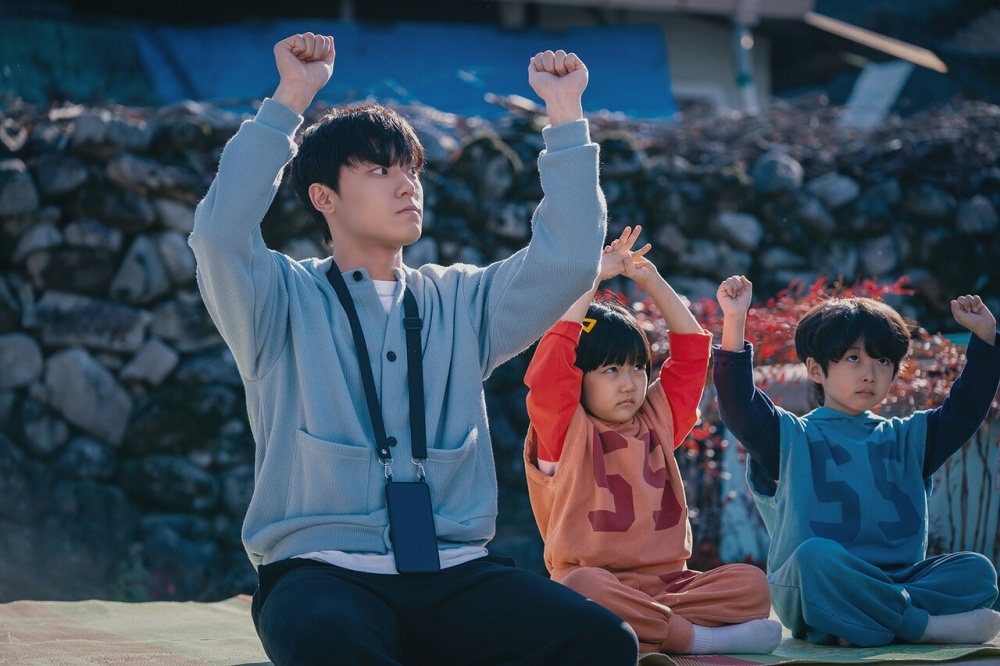 韓劇《壞媽媽》中，李到晛（左）因車禍意外，心智年齡退化到如7、8歲的孩童，常跟村裡的雙胞胎玩在一起。他劇中與媽媽羅美蘭的感人互動，逼哭許多觀眾，在Netflix收視排行已衝上第三名。（翻攝自JTBC）