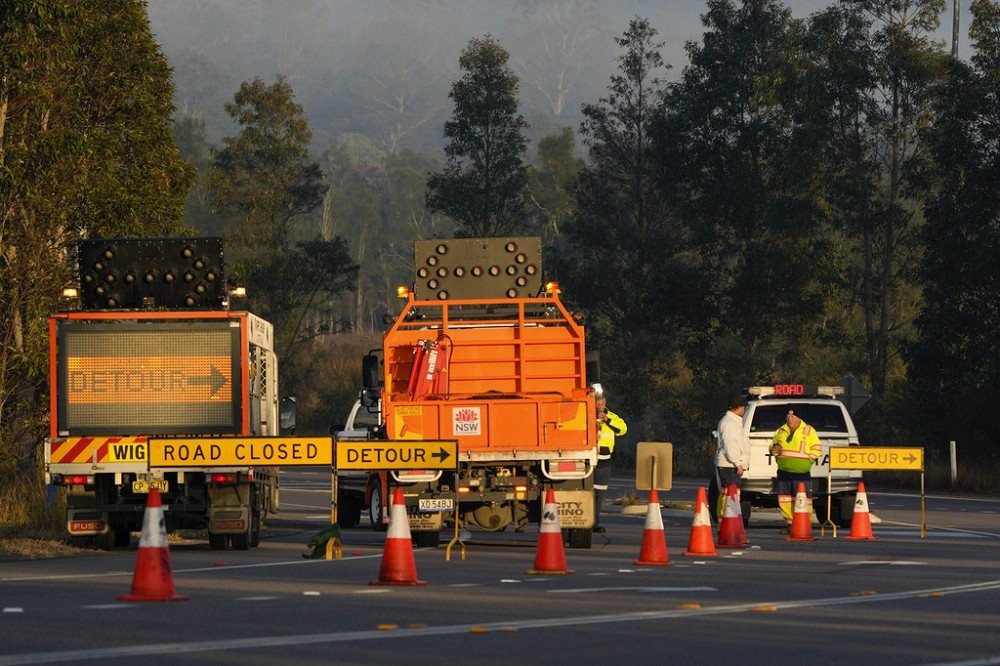 澳洲公路養護單位趕抵巴士翻覆現場，封鎖道路協助搶救與修復路面。（美聯社）