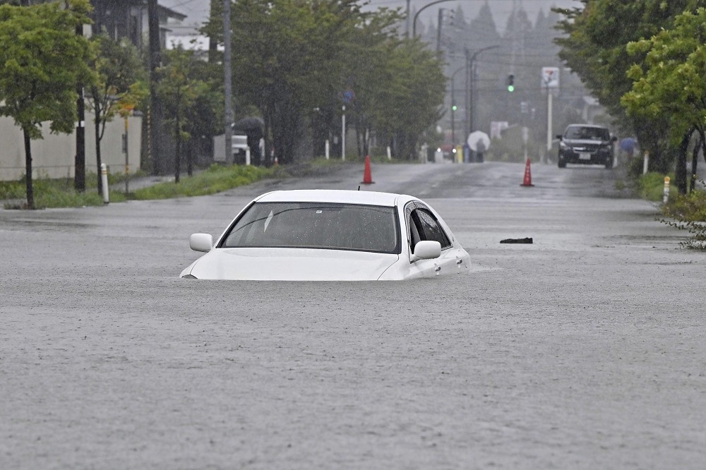 日本秋田的水災讓一輛汽車幾近滅頂。（美聯社）