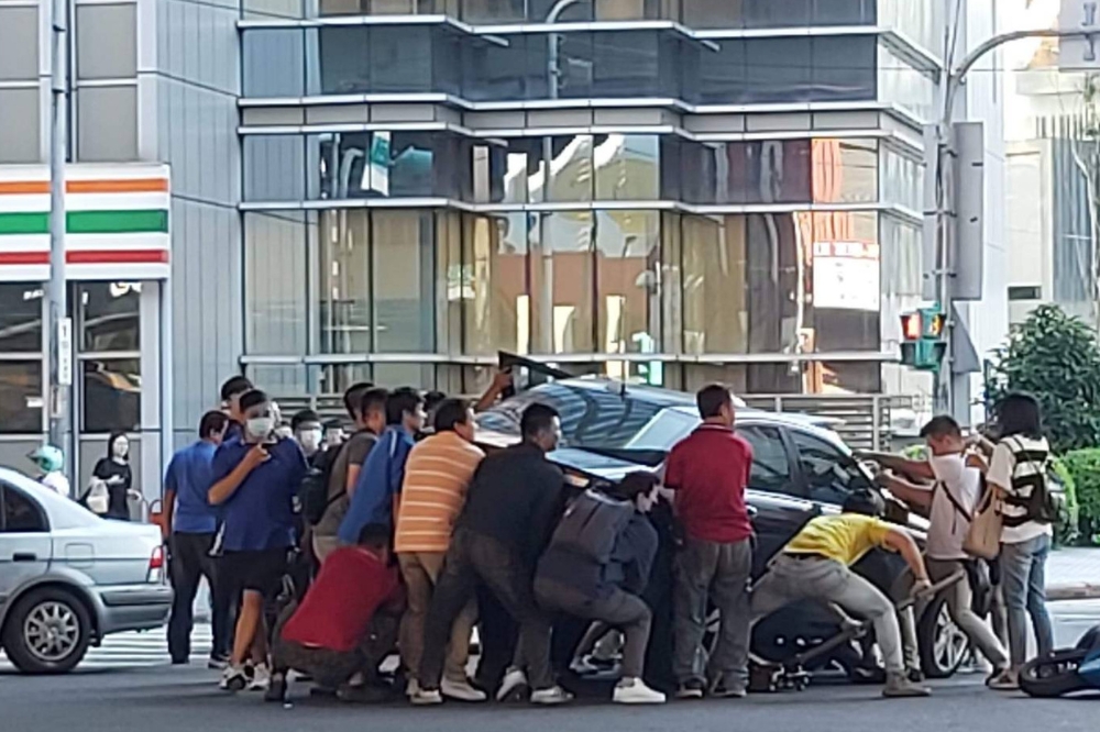 新北市中和區今天發生汽機車碰撞事故，機車騎士被壓在車底，10多人合力抬起車子助其脫困。（取自記者爆料網）
