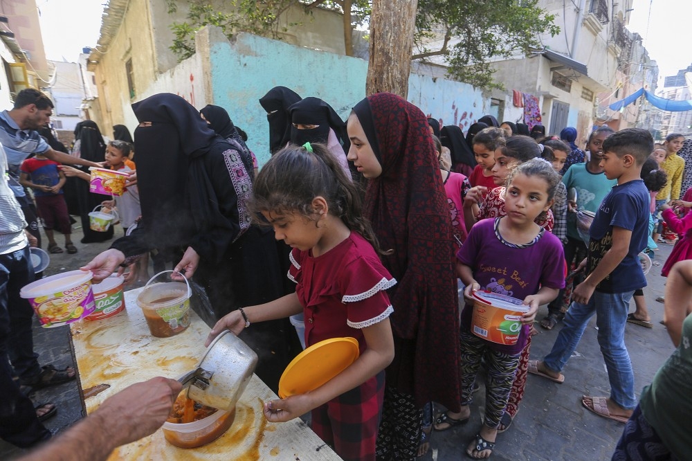 以色列完全封锁加萨地区，并且严控每日送入该区域的饮水与食物，图为加萨南部巴勒斯坦民众排队领取救济物资。（美联社）(photo:UpMedia)