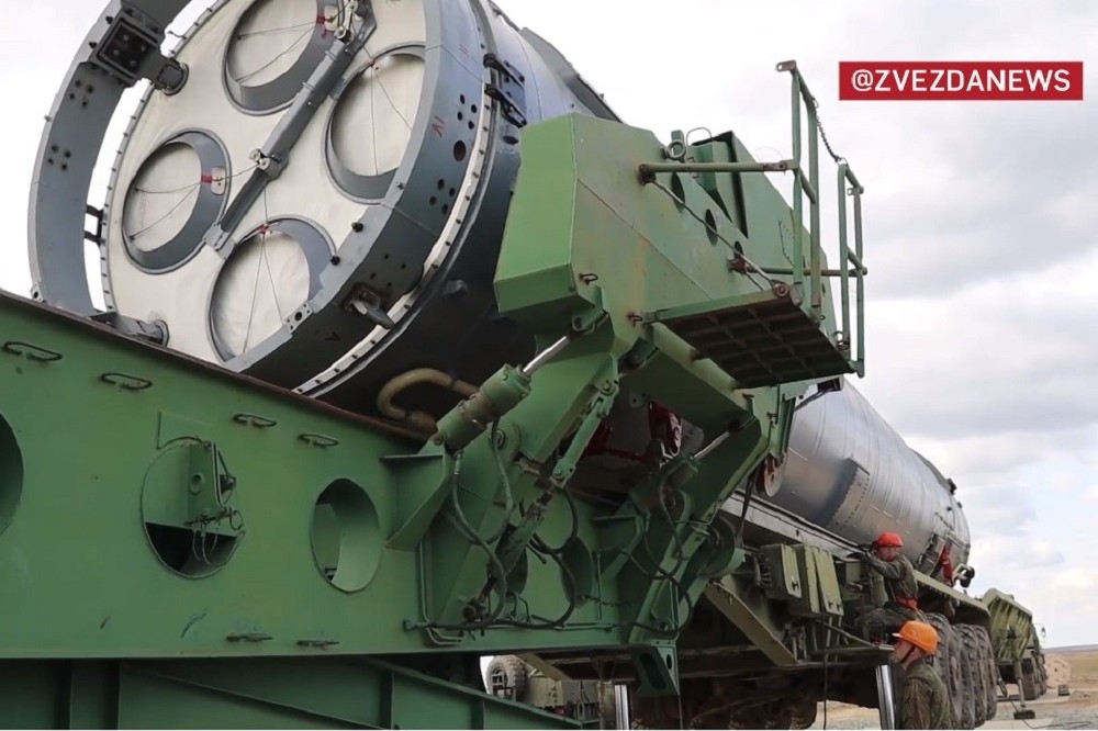 俄軍洲際彈道飛彈安置在填裝機具上，準備送入地下發射井。（截自影片）