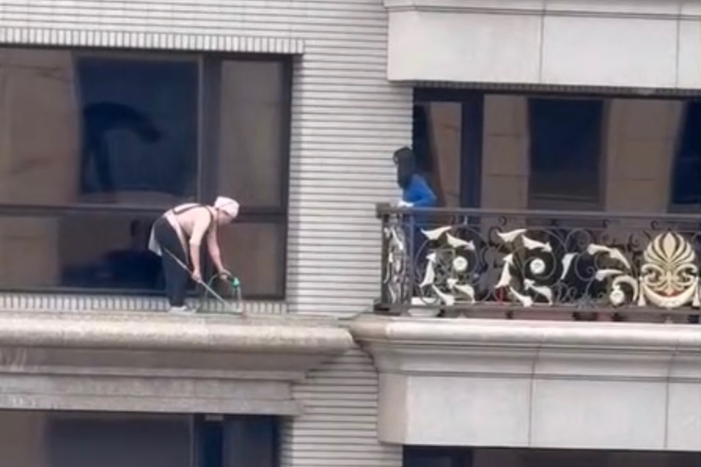 桃園一名女清潔工在沒有任何防護措施下，站在20樓窗外平台上打掃。（擷取自爆料公社二社臉書社團）