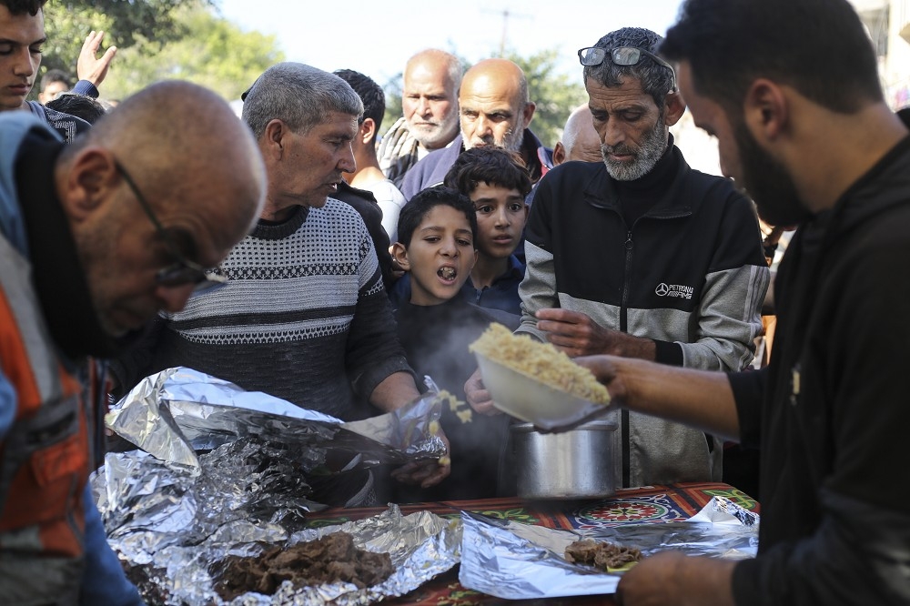 哈玛斯递交释放人质的名单，满足以色列方面的条件后，双方达成停火延长1天的共识，图为加萨民众争先领取救援食物的情形。（美联社）(photo:UpMedia)