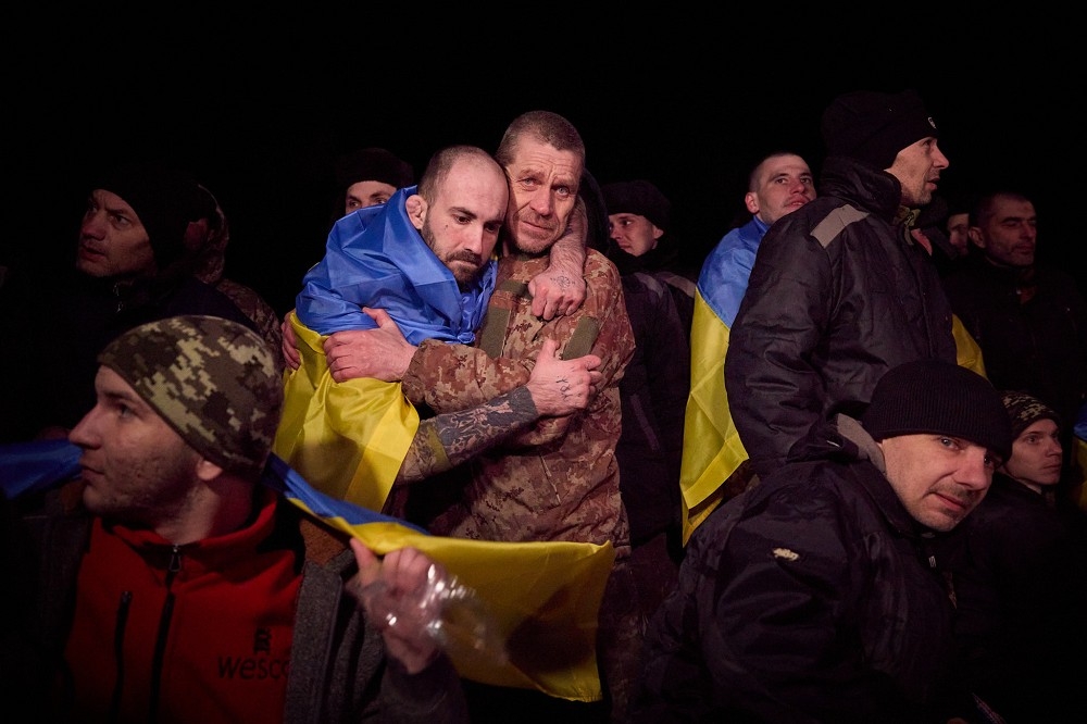 獲釋返國的烏克蘭官兵，身披國旗相擁喜極而泣。（取自X平台）
