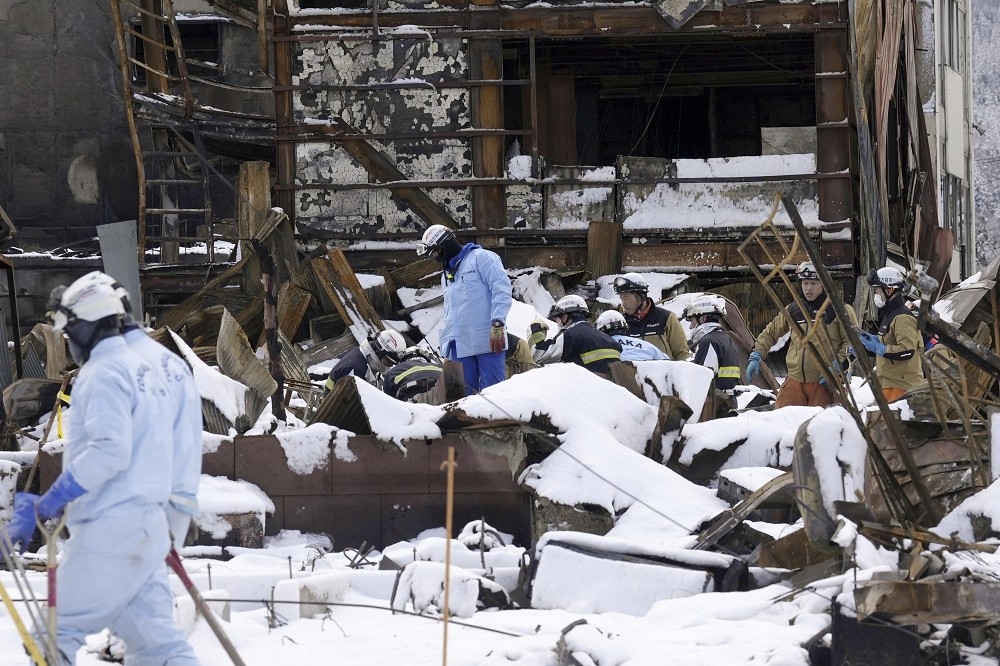 救難人員今天在輪島市的積雪及斷垣殘壁中搜尋失蹤者。（美聯社）