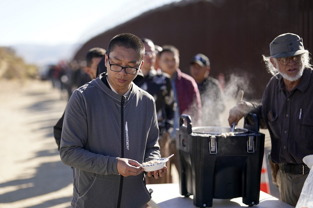 由于经济困顿，从墨西哥偷渡到美国的中国人愈来愈多。图为去年10月一群中国偷渡客在美墨边境领取志工发放的燕麦粥。（美联社）(photo:UpMedia)