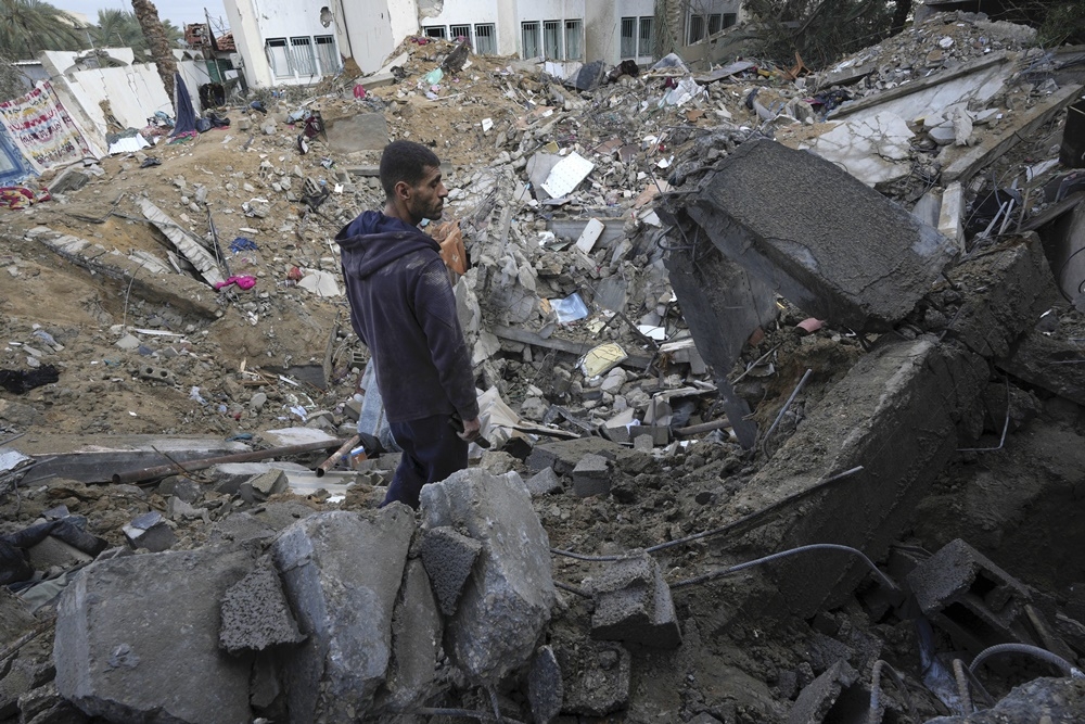加薩中部城鎮迪爾巴拉的住宅區遭以色列炸毀後，當地居民14日望著淪為廢墟的家家園。（美聯社）