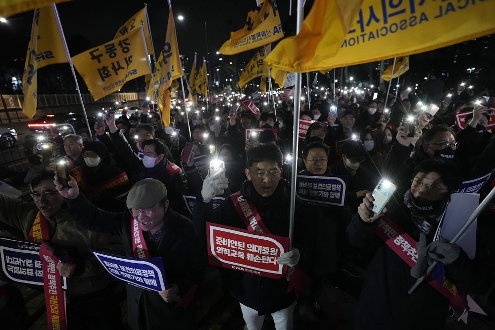在實習醫生為抗議政府擴大招收醫學院學生而集體請辭後，南韓政府下令他們返回工作崗位，並正考慮使用軍醫因應人力短缺問題。圖為首爾總統府附近舉行的反對政府醫療政策的抗議活動。（美聯社）
