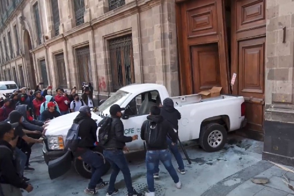 抗議群眾用客貨兩用車後車斗，撞開墨西哥總統府大門。（截自影片）