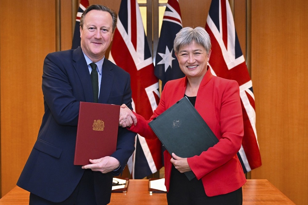澳洲外長黃英賢與英國外交大臣卡麥隆，21日在國會大廈完成協議簽署後握手致意。（美聯社）