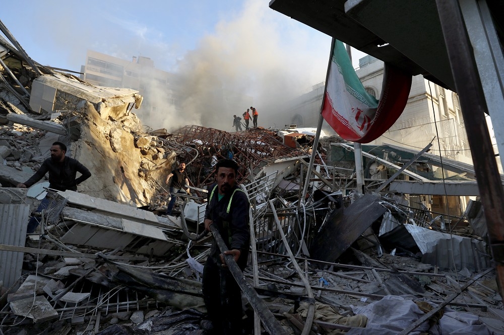 伊朗駐敘利亞大馬士革領事館4月1日被空襲炸成廢墟，瓦礫堆中還倒臥著伊朗國旗旗桿。（美聯社）