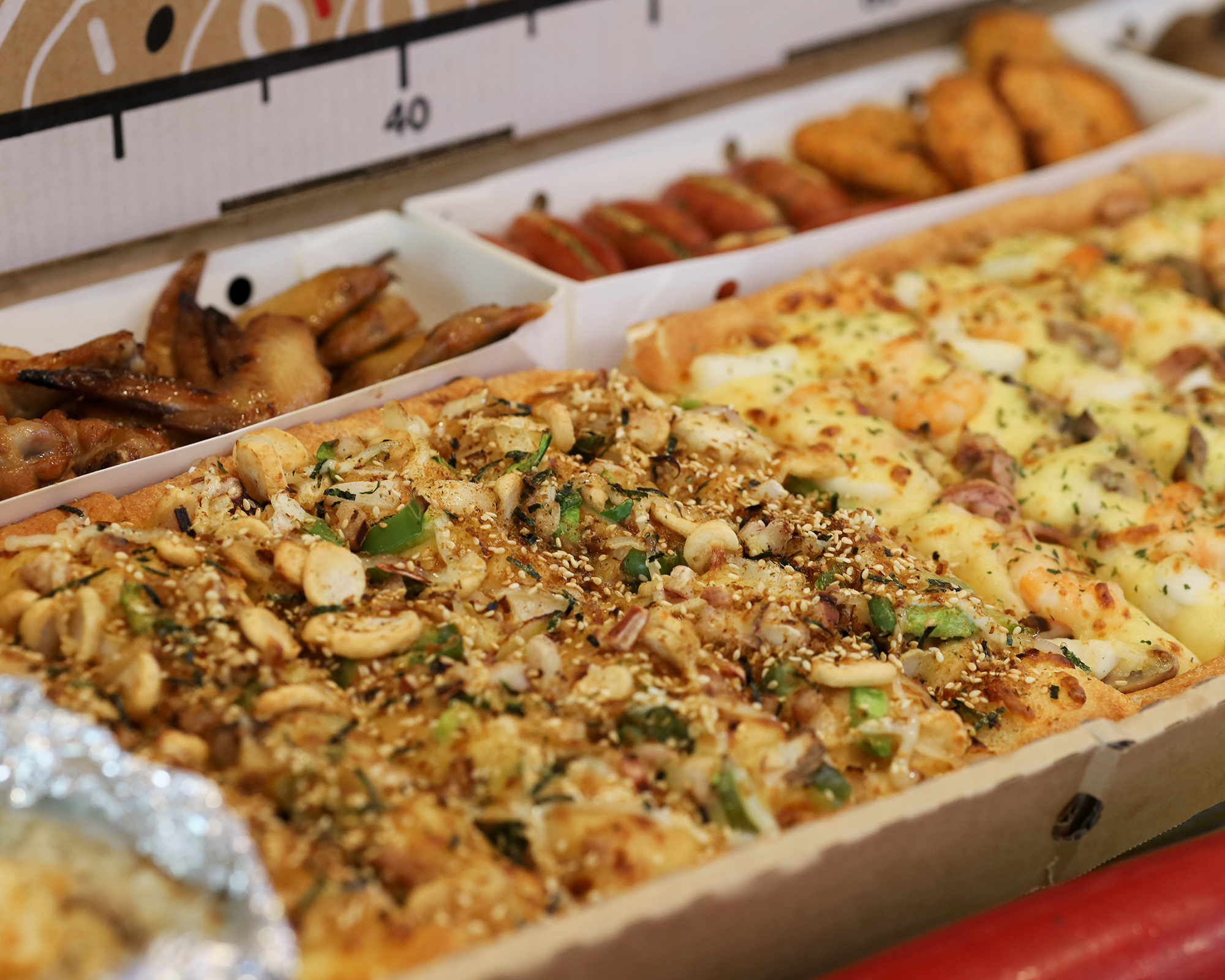 必勝客「一公尺派對巨飽盒」包含大比薩、紙包筆管麵、BBQ 烤雞、薯金幣、德國芝心腸、麻糬 QQ 球、黃金和風鱈魚塊