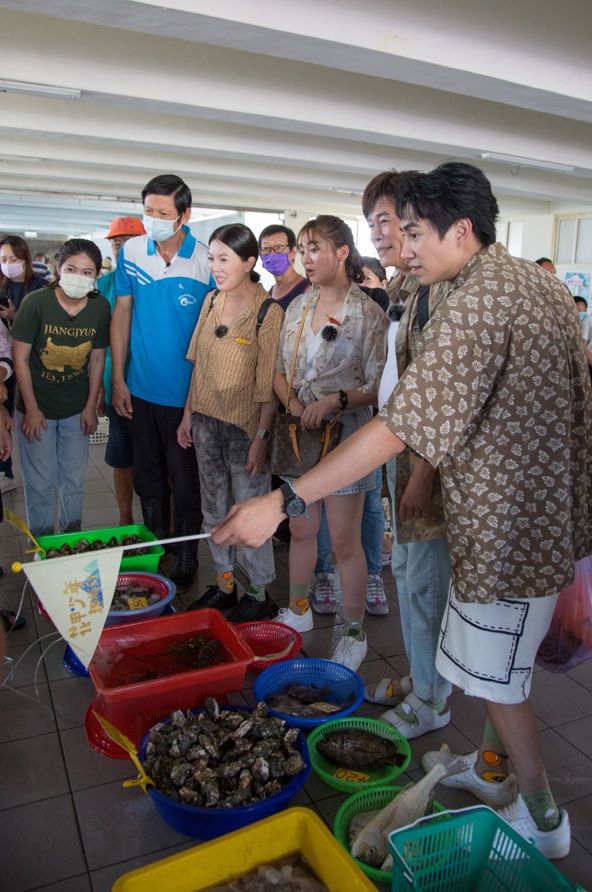 潘君侖（右）在《花甲少年趣旅行》帶大家到漁市瞭解漁貨拍賣過程。（東森提供）