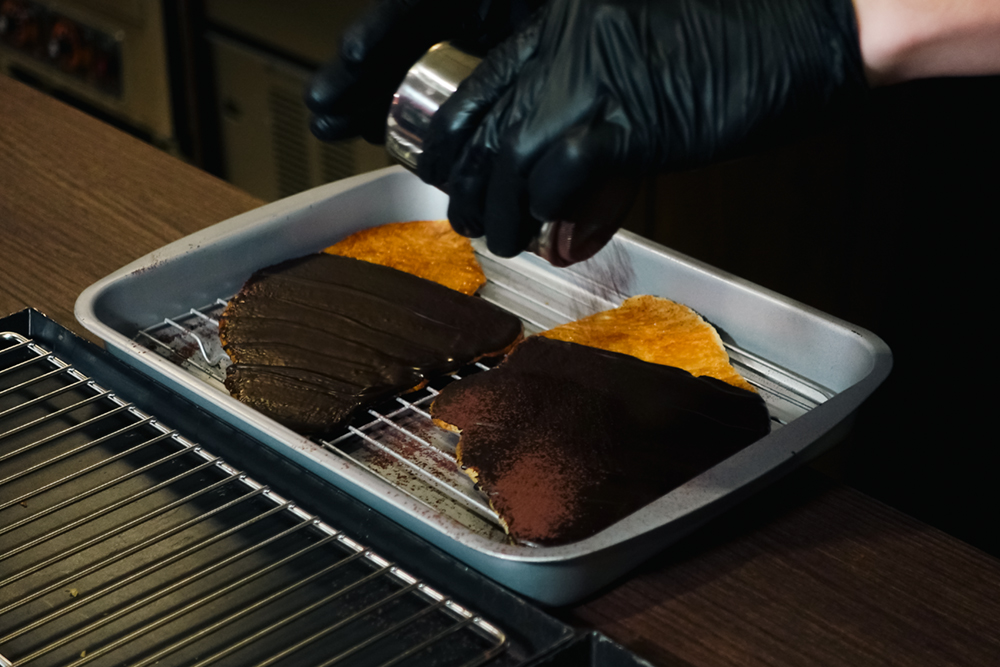 透過機器壓扁烤製而成後，再淋上黑巧克力並撒上可可粉，「黑巧克力扁可頌」吃起來不會過於甜膩